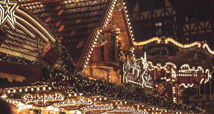 Illuminated stalls at a Christmas market at night.
