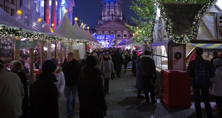 Crowded street at a Christmas market with festive lights.
