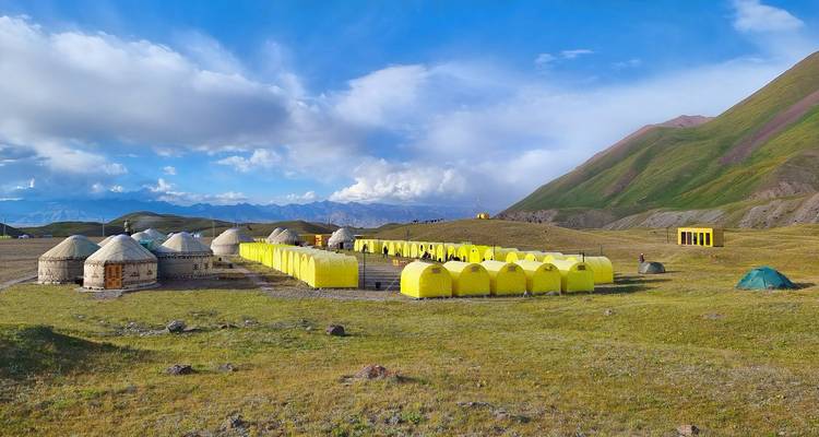 Vue panoramique d'un terrain de camping avec des tentes jaunes et des yourtes.