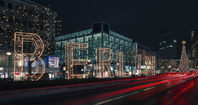 Illuminated city scene at night with 'BERLIN' in lights and streaks from vehicle lights.