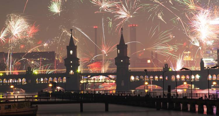 Fireworks over Oberbaum Bridge in Berlin reflecting in the water at night.