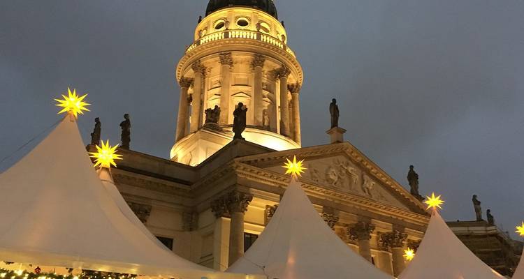 Domed building at a Christmas market with tents and lights in the evening.