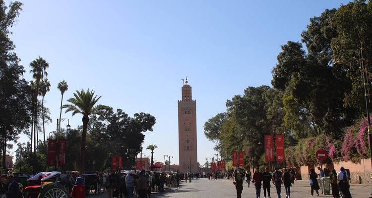Large mosque tower with people walking around it.