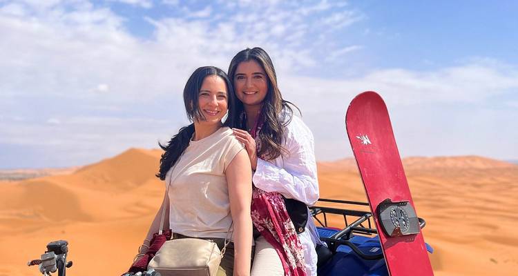 Two women posing with sand dunes in the background.