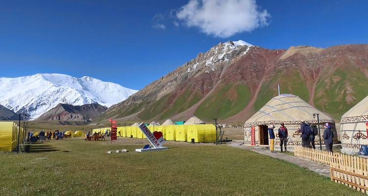Camp with yurts at the base of snow-covered mountains