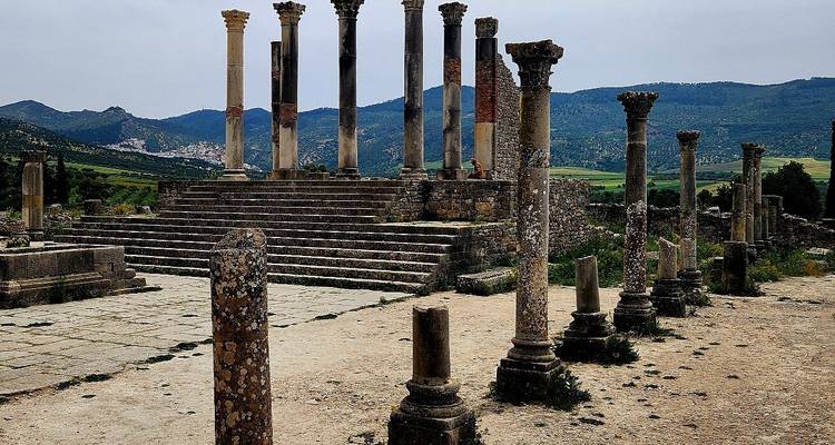 Ruines de colonnes antiques avec toile de fond montagneuse.