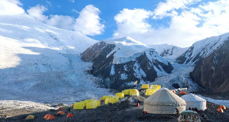 Camp de base avec des tentes jaunes et une montagne enneigée.