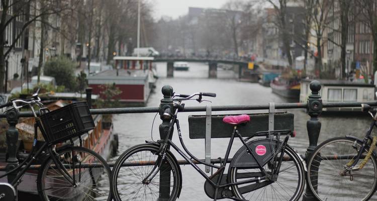 Canal avec des vélos garés sur un pont et des bâtiments historiques en arrière-plan.