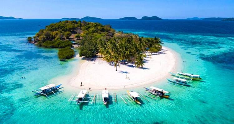 Petite île tropicale avec des bateaux et une plage de sable blanc.