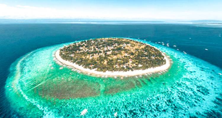 Vue aérienne d'une île circulaire avec une eau turquoise éclatante qui l'entoure.