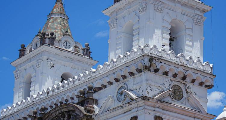 Weiße Kirchtürme mit Zifferblättern vor einem klaren blauen Himmel.