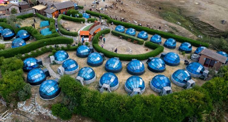 Vue aérienne d'un terrain de camping avec des tentes dômes bleues et des personnes qui marchent.