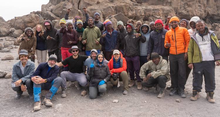 Grote groep poserend op rotsachtig terrein, waarschijnlijk een trekkinggroep.