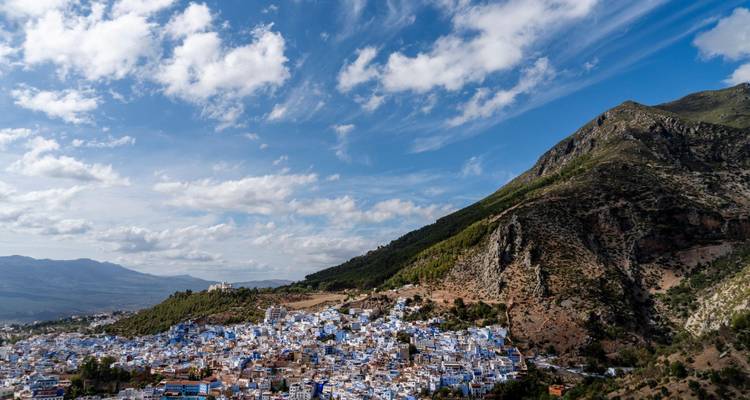 El pueblo azul de Chefchaouen extendiéndose por las colinas con un cielo espectacular y montañas escarpadas.