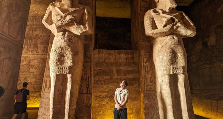 Una persona está mirando hacia arriba a grandes estatuas dentro de un templo.