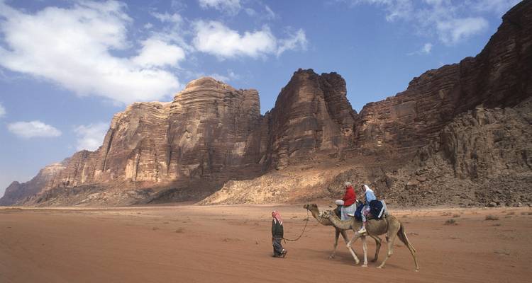 Personas montando camellos en montañas del desierto.