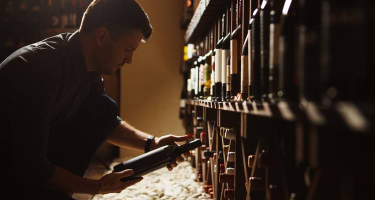 Persoon die wijnflessen selecteert in een kelder.