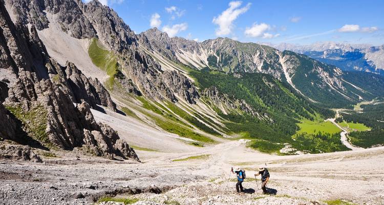 Hikers climbing a mountainous trail with rugged slopes.