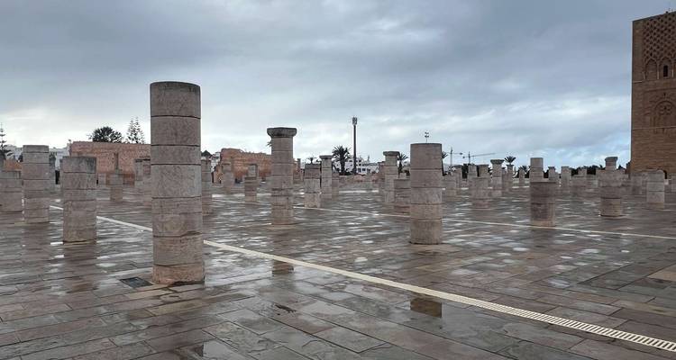 Stone columns on a wet courtyard under cloudy sky.