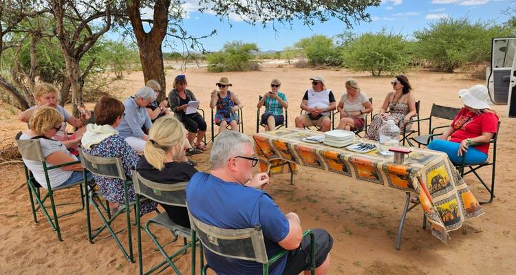 Groupe de personnes assises autour d'une table dans un paysage aride.