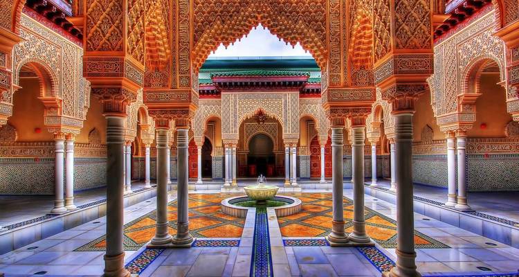 Cour marocaine ornée avec des carreaux et menuiseries complexes.