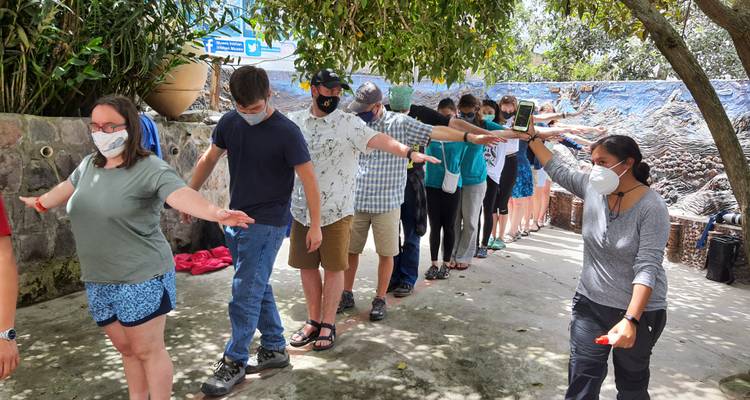Groupe de personnes debout en ligne avec les bras étendus, portant des masques.