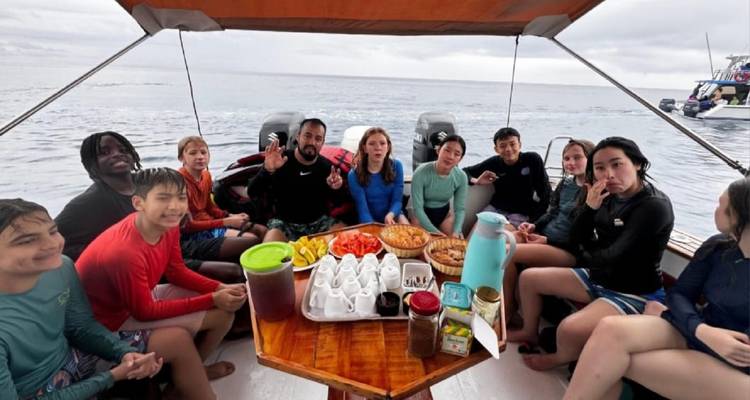 Groupe de personnes profitant d'un repas sur un bateau avec vue sur l'océan.