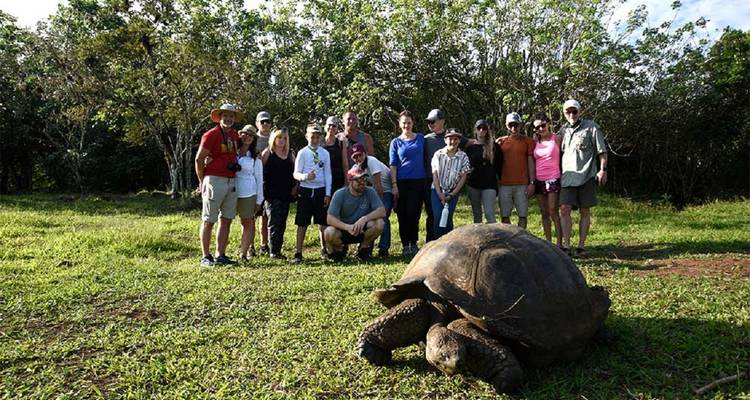 Groupe de personnes autour d'une tortue géante aux Galápagos.