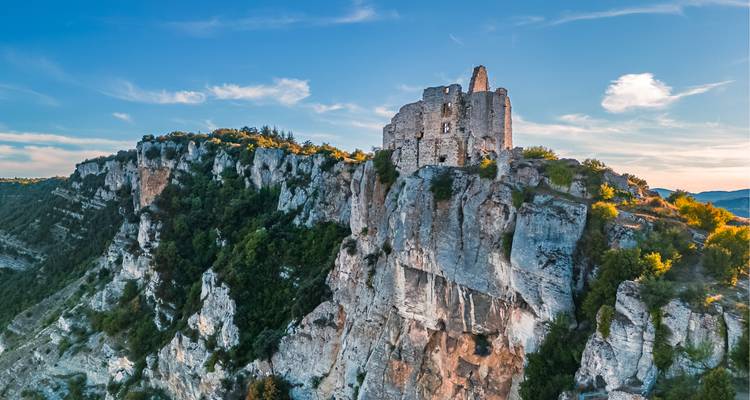 Ruines d'un château perché sur une falaise spectaculaire au coucher du soleil.