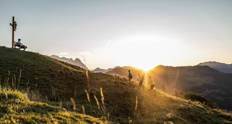 Personas sentadas en una colina al atardecer.
