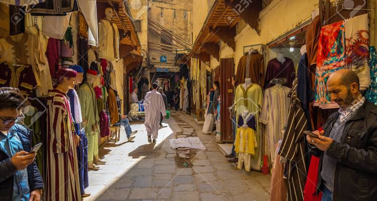 Rue du marché au Maroc avec des gens et des vêtements colorés.