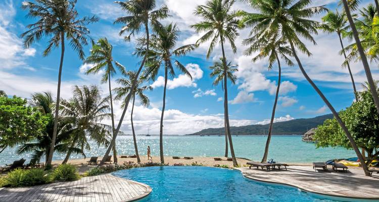 Plage tropicale avec des palmiers et une piscine avec vue sur l'océan.