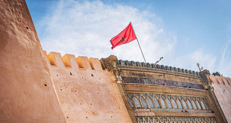 A historical fortress wall with Moroccan flag waving.