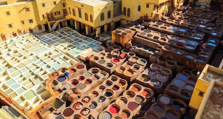 Traditional tannery with colorful dye pits and yellow buildings.