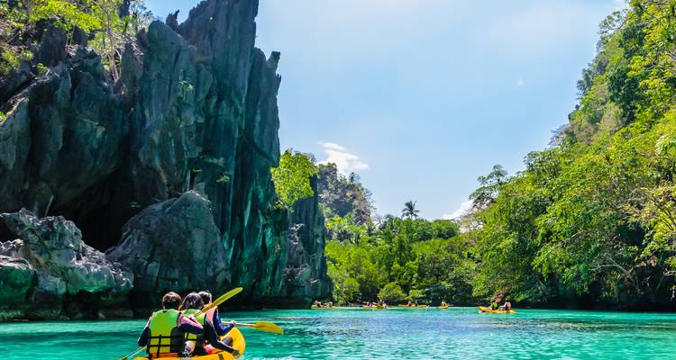 Des kayakistes explorant un lagon magnifique entouré de falaises.