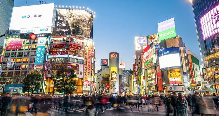 Les lumières du soir et les panneaux publicitaires illuminent le passage piéton bondé de Shibuya à Tokyo.