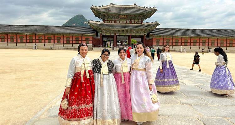 Frauen in Hanbok posieren vor einem koreanischen Palast.