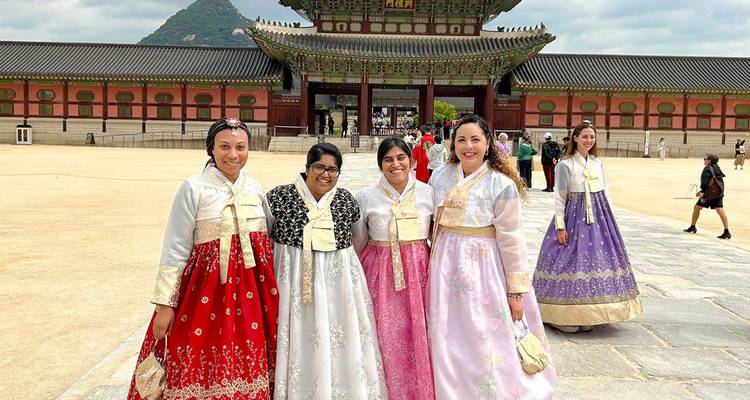 Women wearing colourful hanbok pose in front of Gyeongbokgung Palace in Seoul.