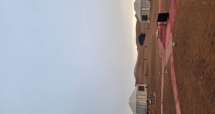 Woestijnkamp met verschillende tenten en een heldere lucht op de achtergrond.