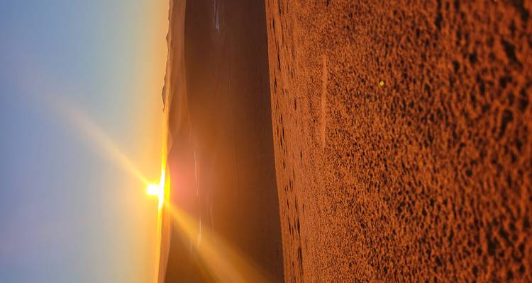 Woestijnlandschap met zonsondergang en zandduinen.