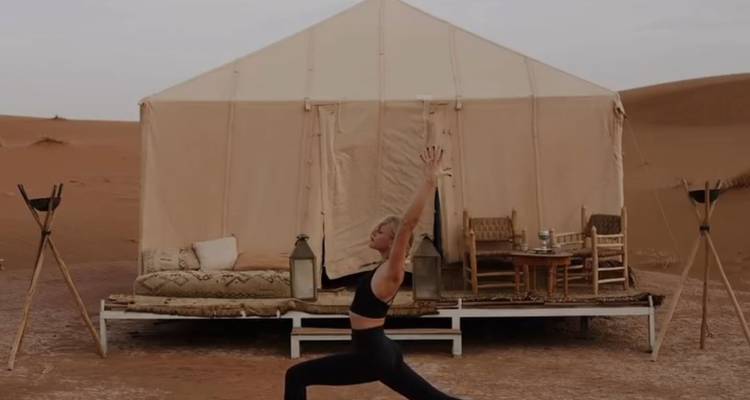 Personne faisant du yoga devant une tente de désert.