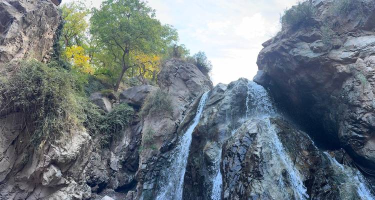Cascade tombant sur des rochers entourés de végétation.