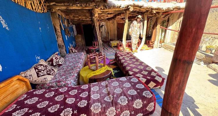 Coin salon extérieur rustique avec des couvertures et coussins colorés.