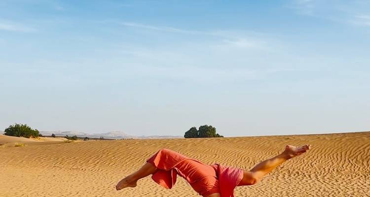 Personne faisant du yoga dans le désert avec un ciel dégagé.
