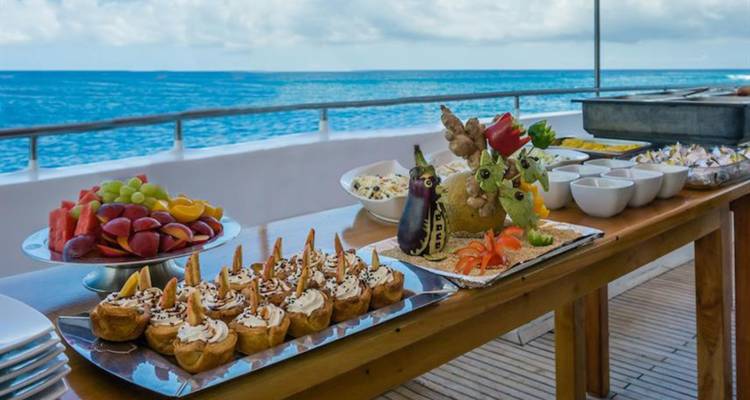 Buffet alimentaire installé en plein air sur le pont d'un yacht avec vue sur mer.