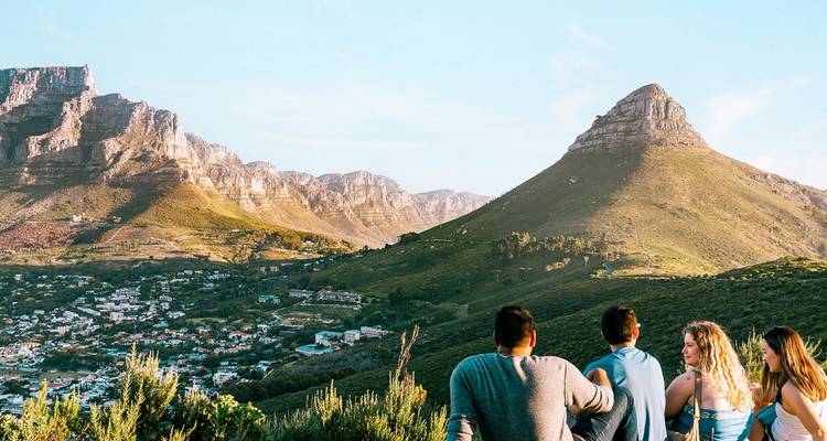 Reizigers ontspannen op een heuvel met uitzicht op Kaapstad met Lion's Head en Tafelberg in zicht.