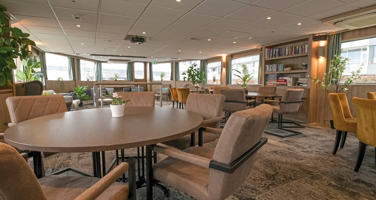 Innenraum eines modernen, gemütlichen Essbereichs mit Tischen und Stühlen.