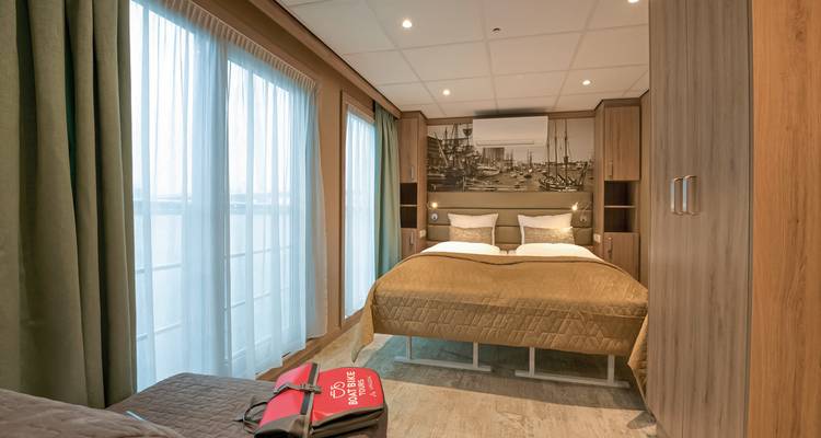 Modernes Doppelschlafzimmer mit verhangenen Fenstern und neutraler Einrichtung.