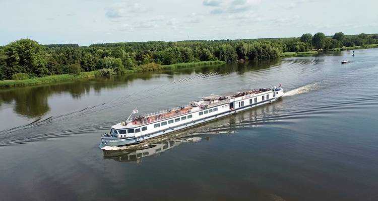 Panoramablick auf ein langes Flussboot, das auf einem ruhigen Fluss fährt.