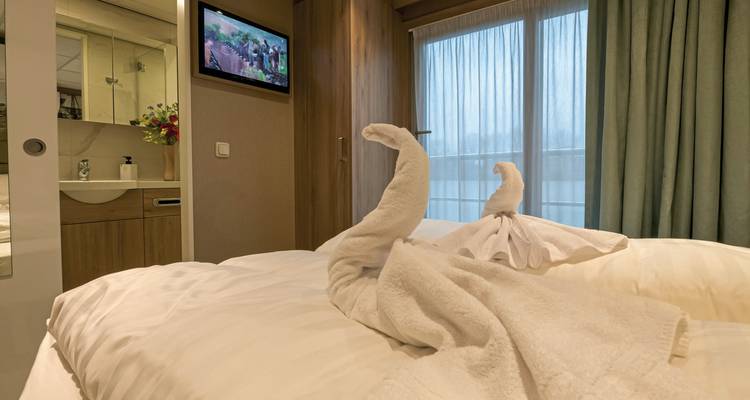 Innenraum einer gemütlichen Hütte mit einem Bett und gefalteten Handtuchtieren.